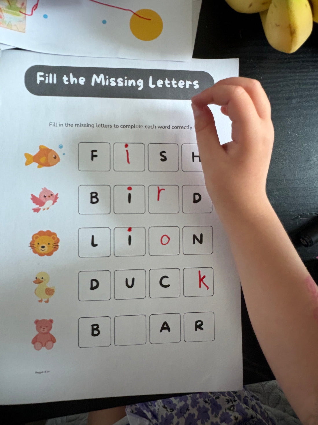 A child filling in a printable missing letters worksheet at home