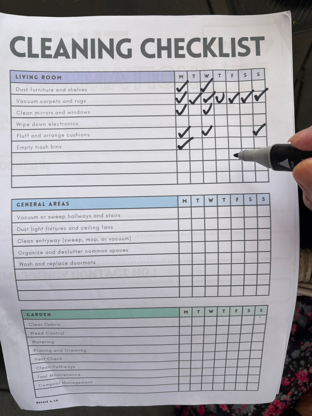 Cleaning checklist with a hand holding a pen, checking off tasks.