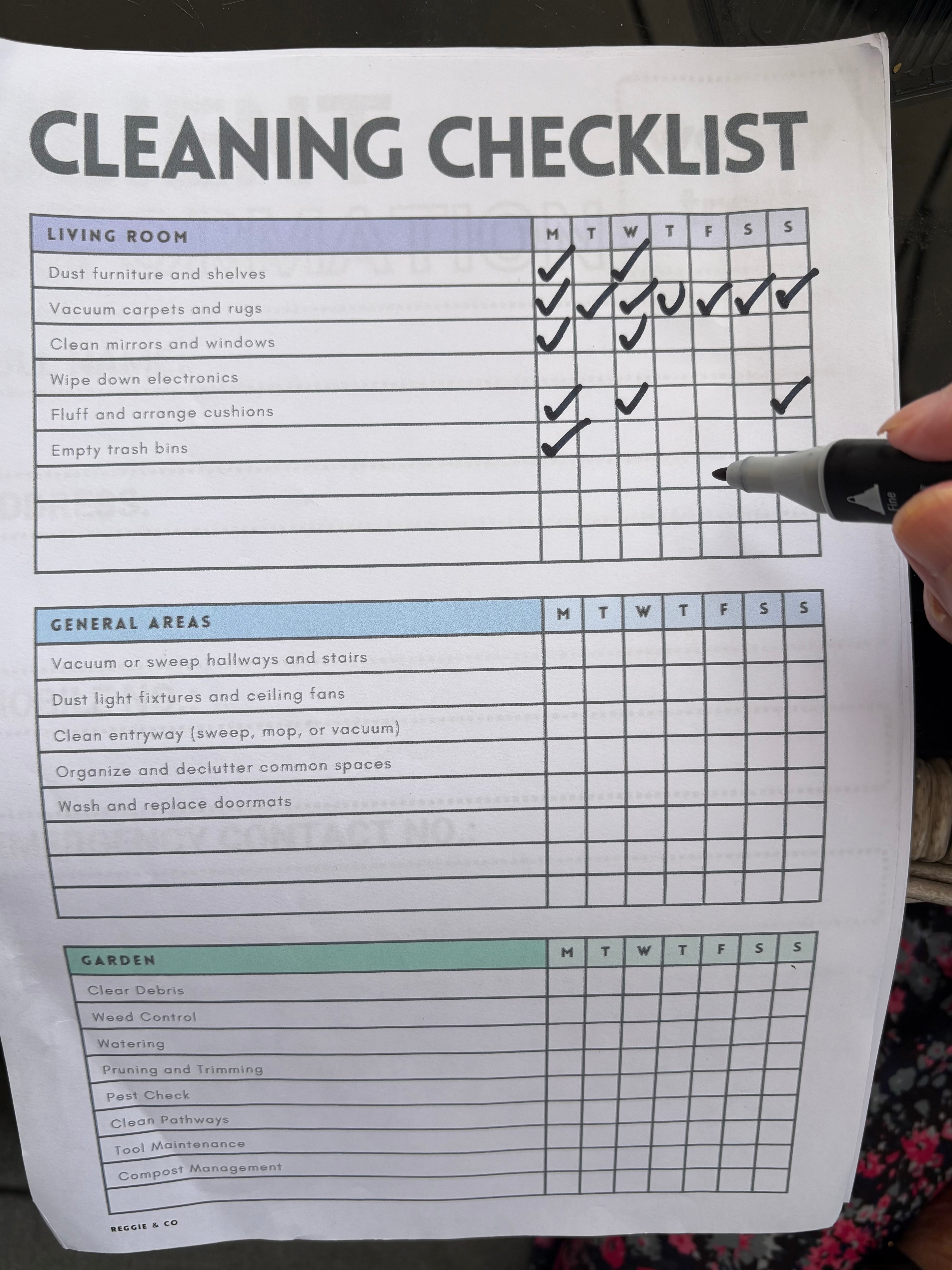 Cleaning checklist with a hand holding a pen, checking off tasks.