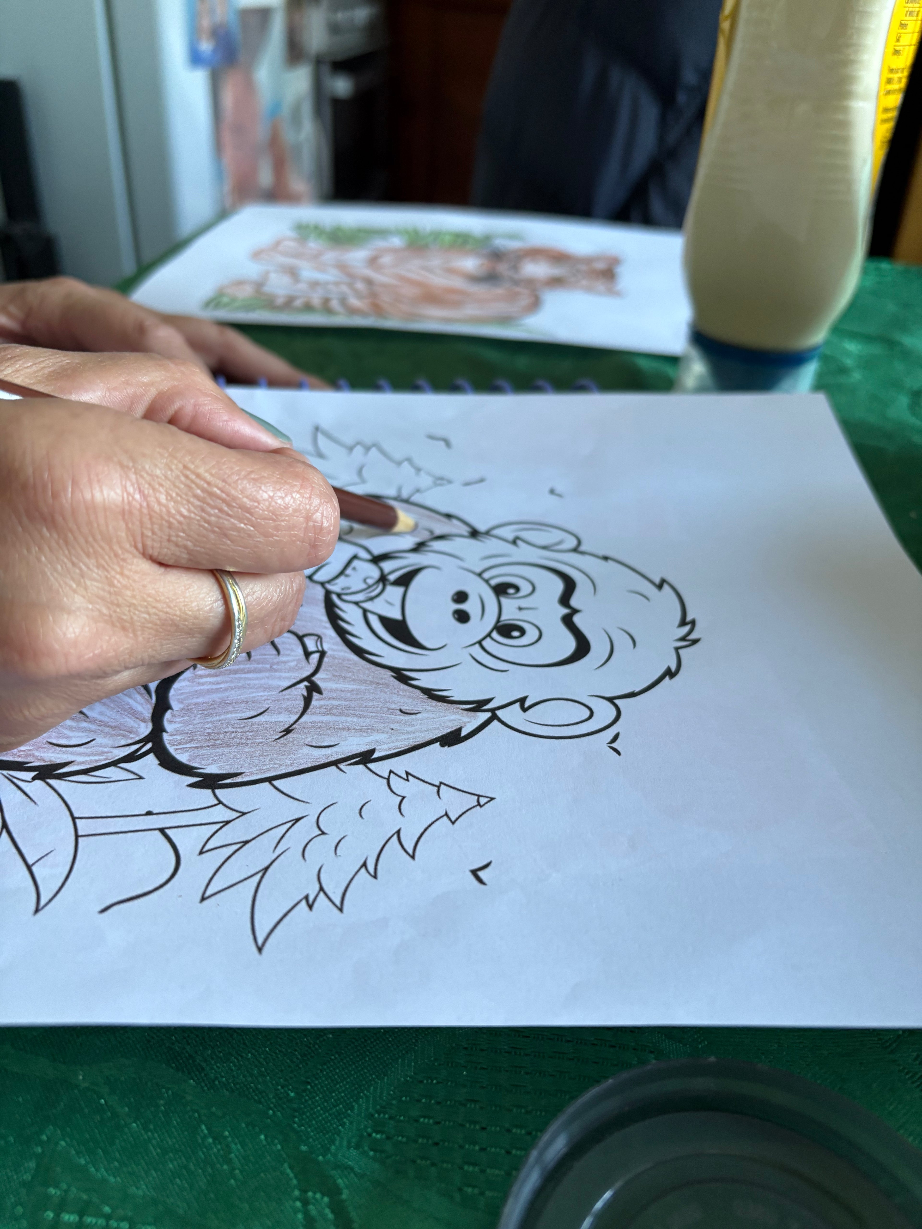 Person coloring a cartoon character on a piece of paper with a marker.