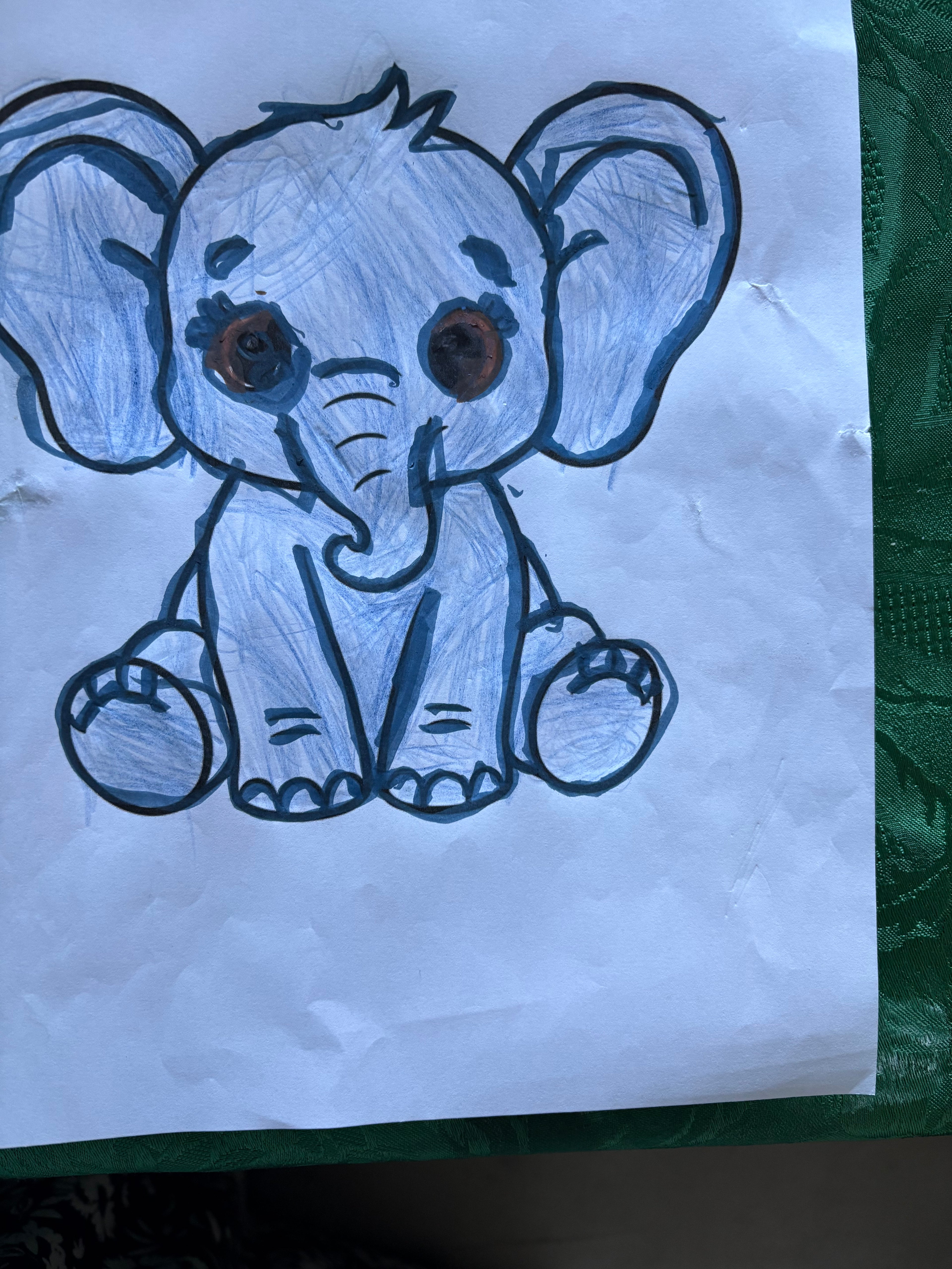Cartoon elephant drawing on a white sheet of paper with a green textured background.